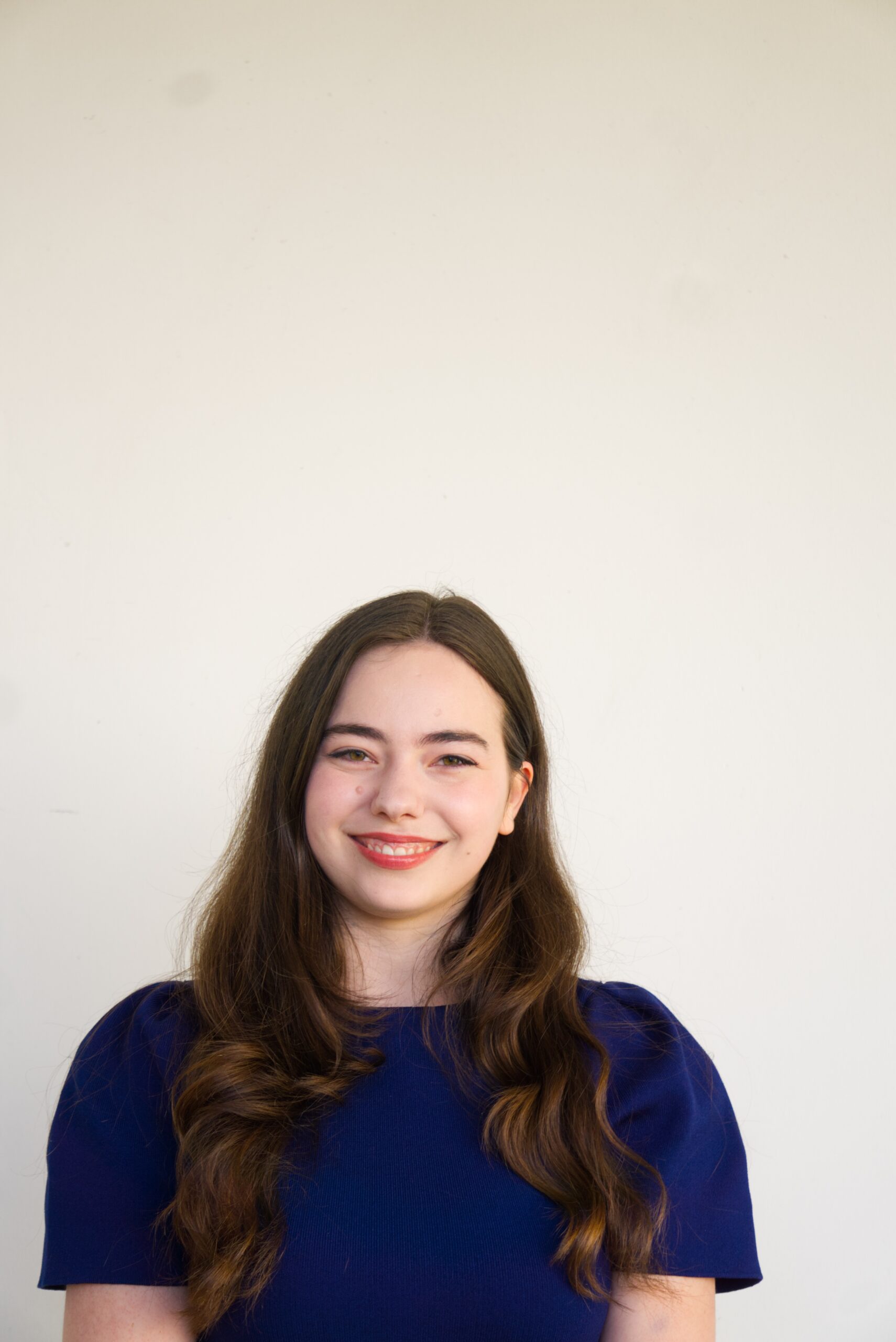 Johanna Marlies Kézdi smiling, standing before a white background